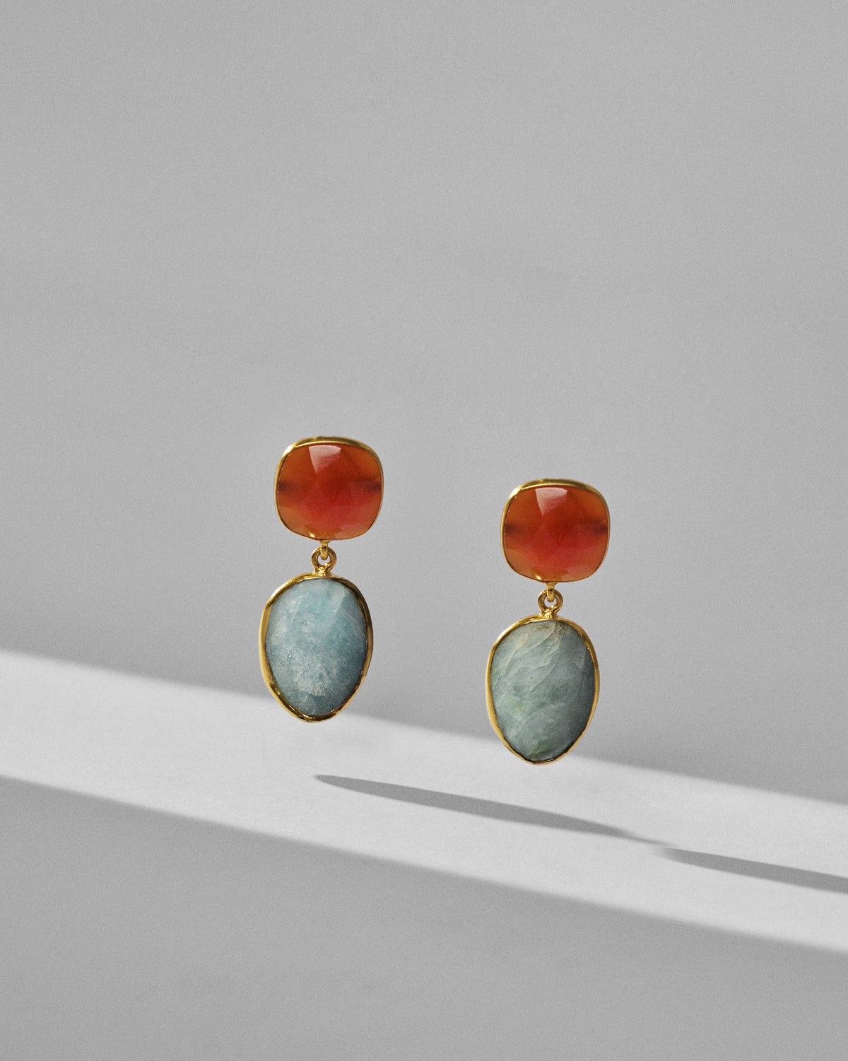 Pair of orange and pale blue icy amber earrings standing upright.