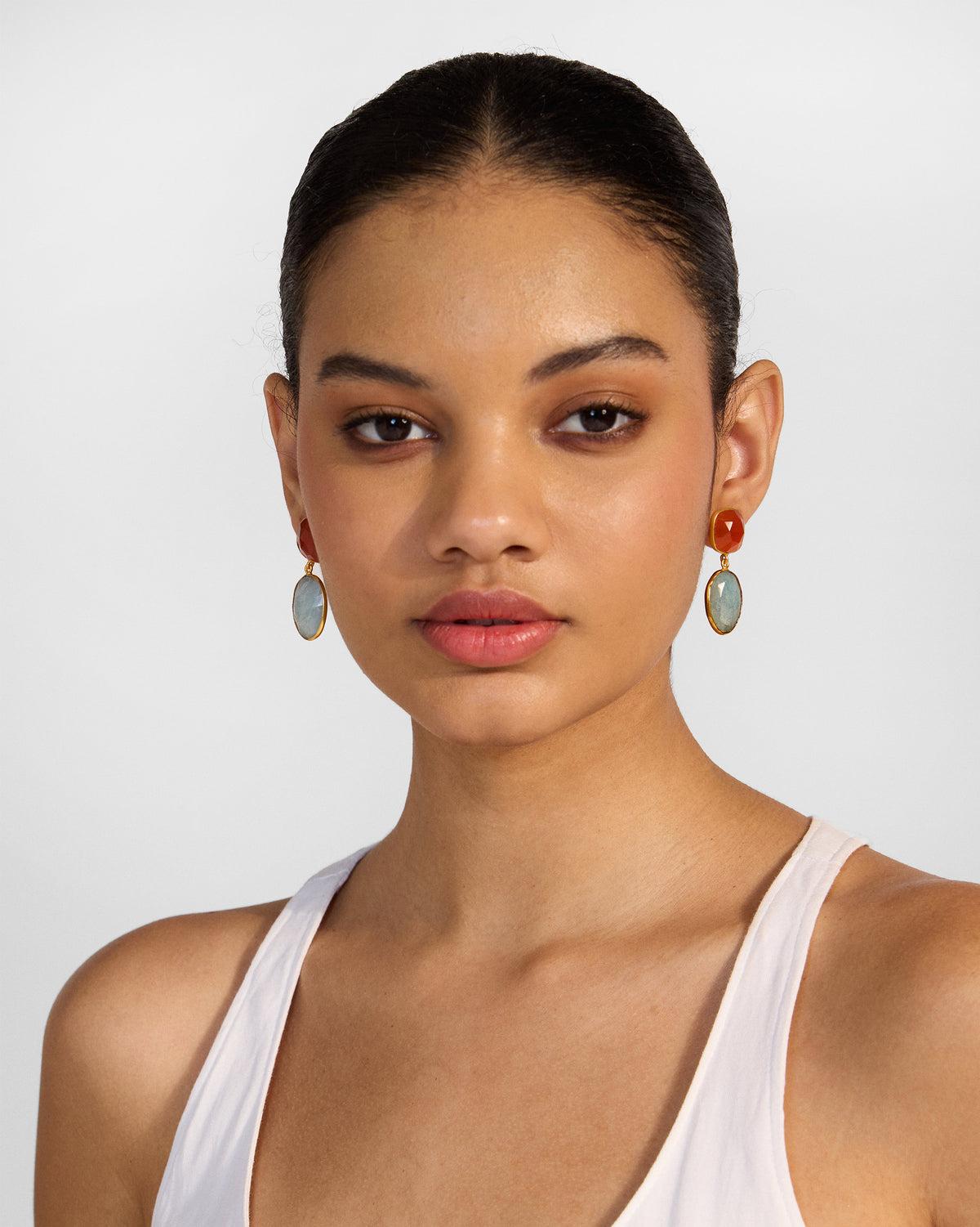Person wearing orange and pale blue icy amber drop earrings.