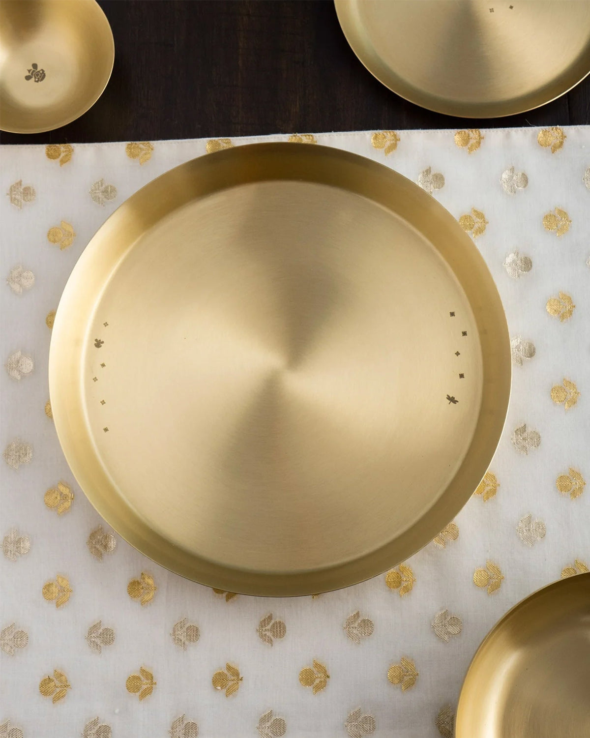 Overhead brass Madhu thali with a small bird and star motif.