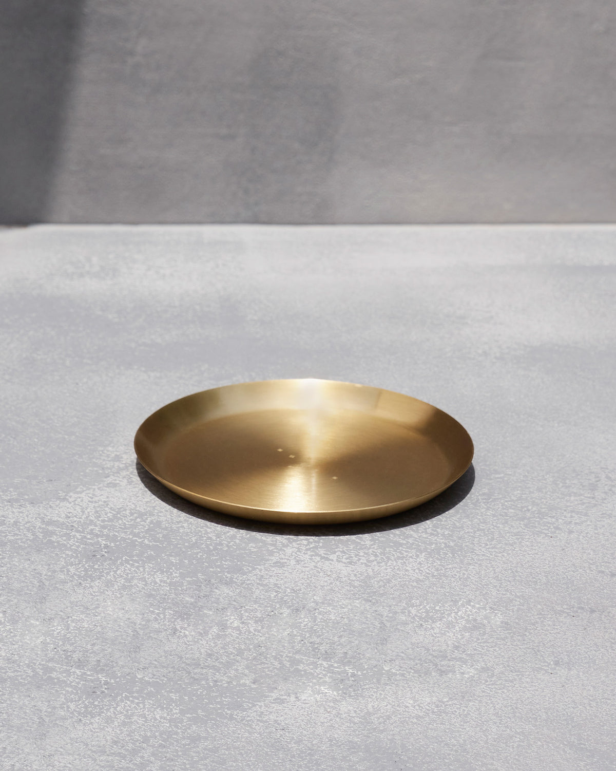 Brushed brass Madhu quarter plate with a shallow flared rim.