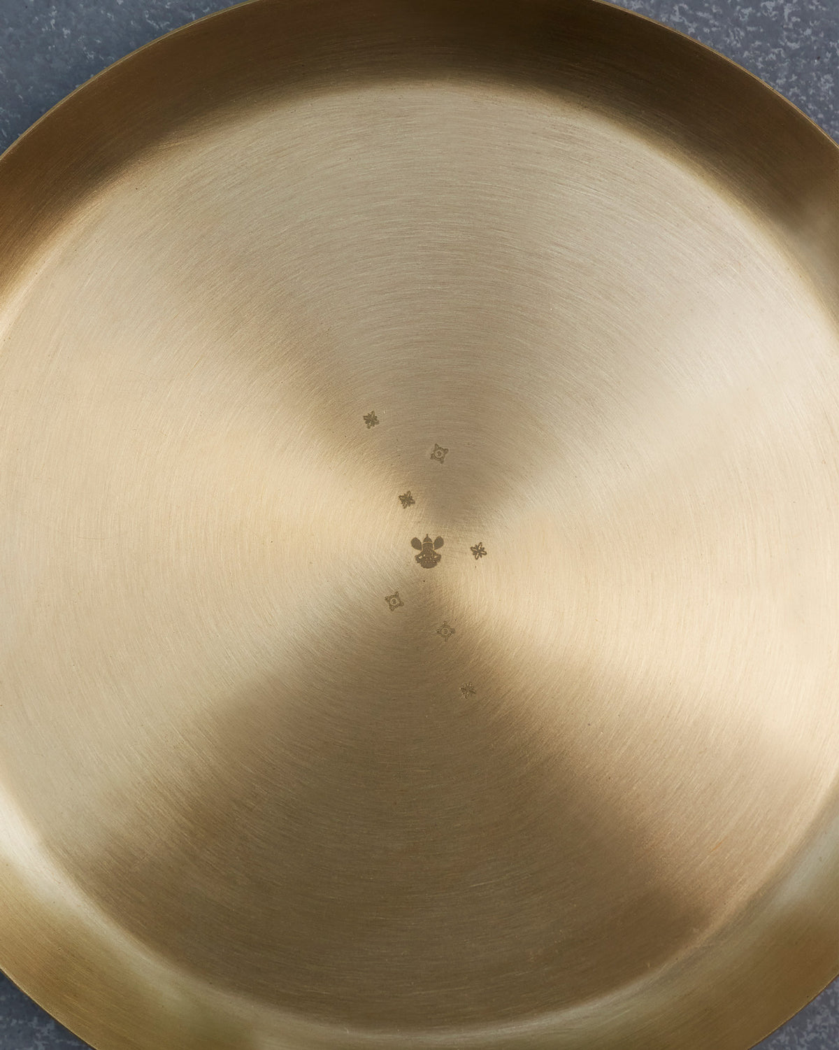 Close-up of a brass Madhu quarter plate showing a small star motif.