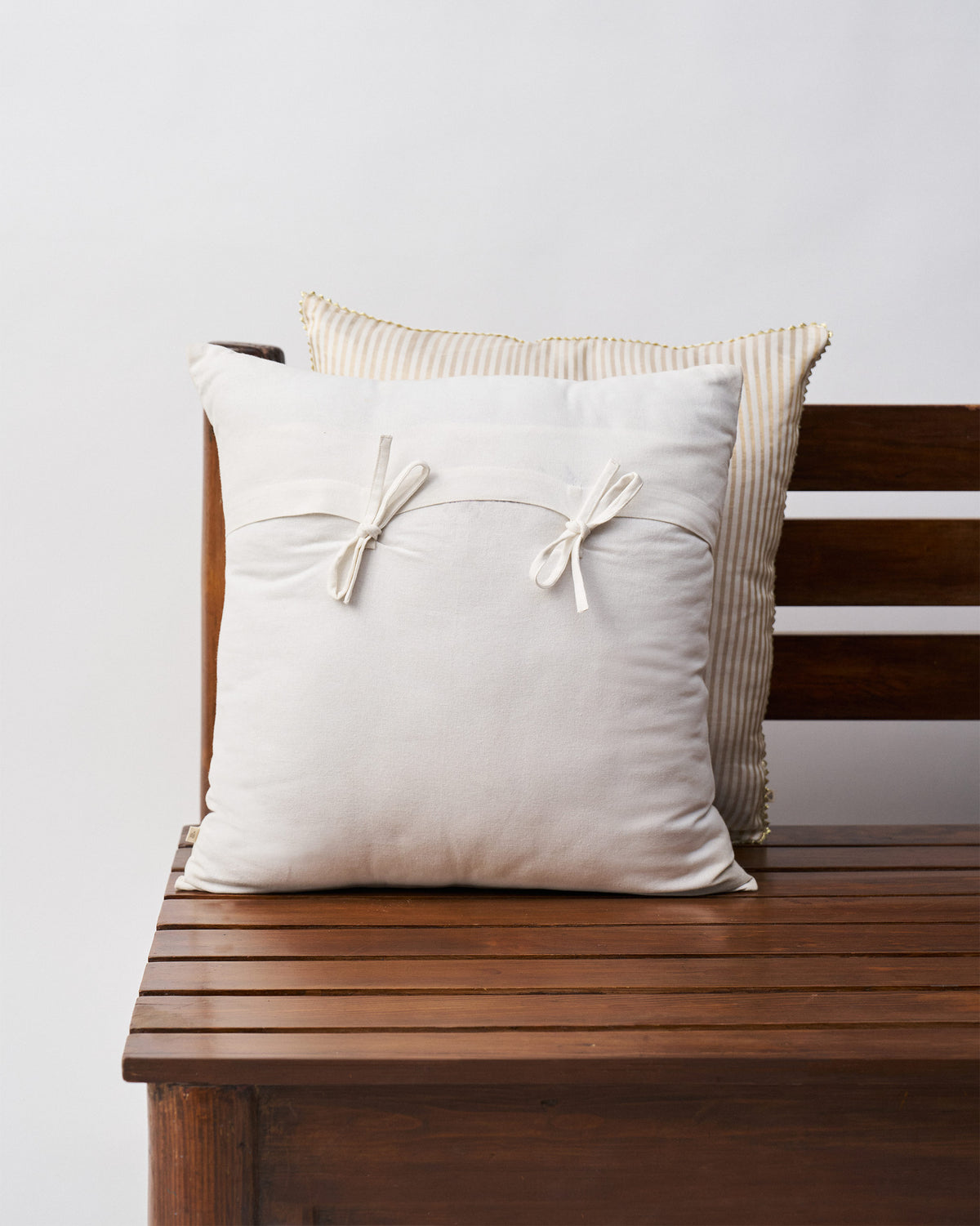 Back of Golden Palm Cushion Cover in cream with two fabric bows.