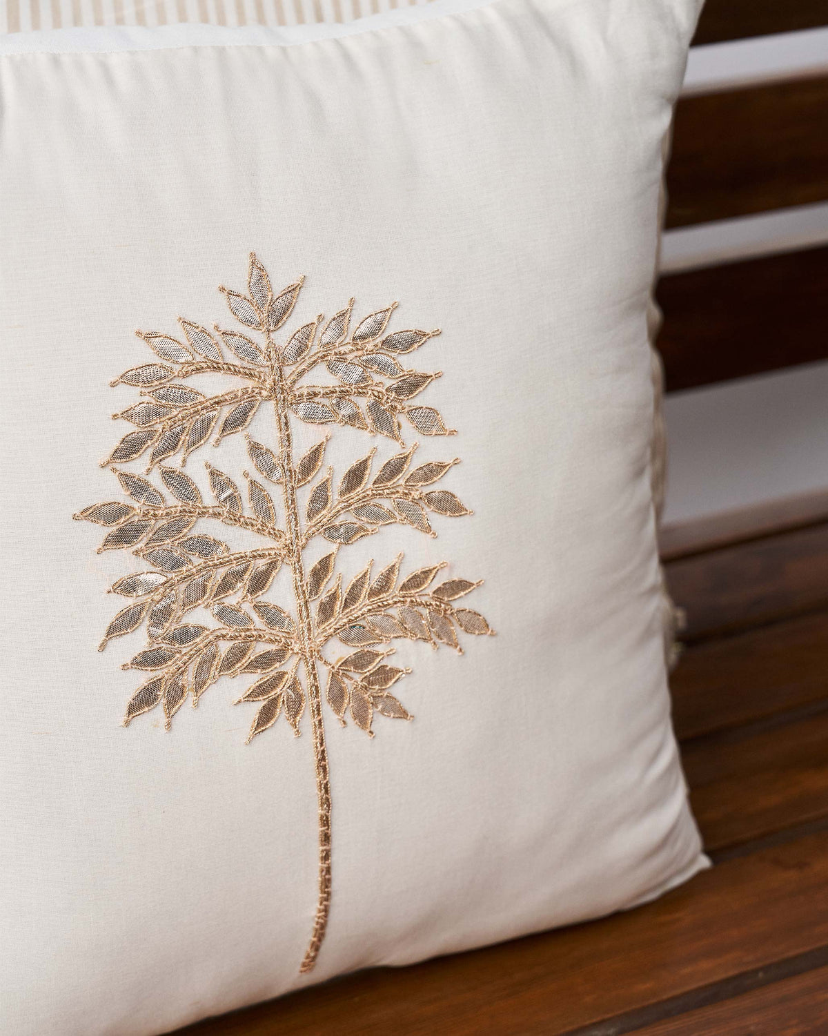 Close-up of Golden Palm Cushion Cover showing gold embroidered leaves on cream fabric.