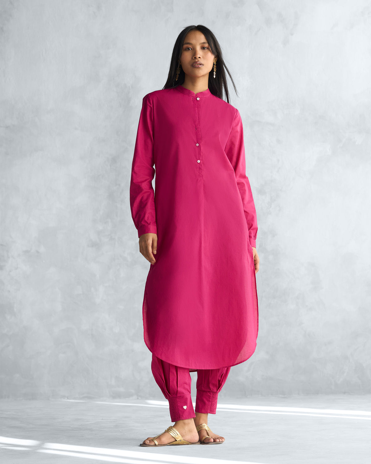 Person wearing a berry long kurta with high side slits and a curved hem.