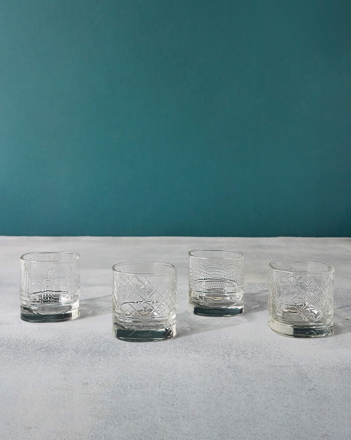 Set of four Mahi whiskey glasses with mixed etched patterns.