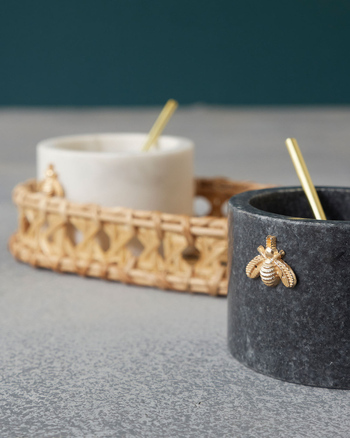 Close-up of a Garo charcoal marble pot with a gold bee motif and spoon.