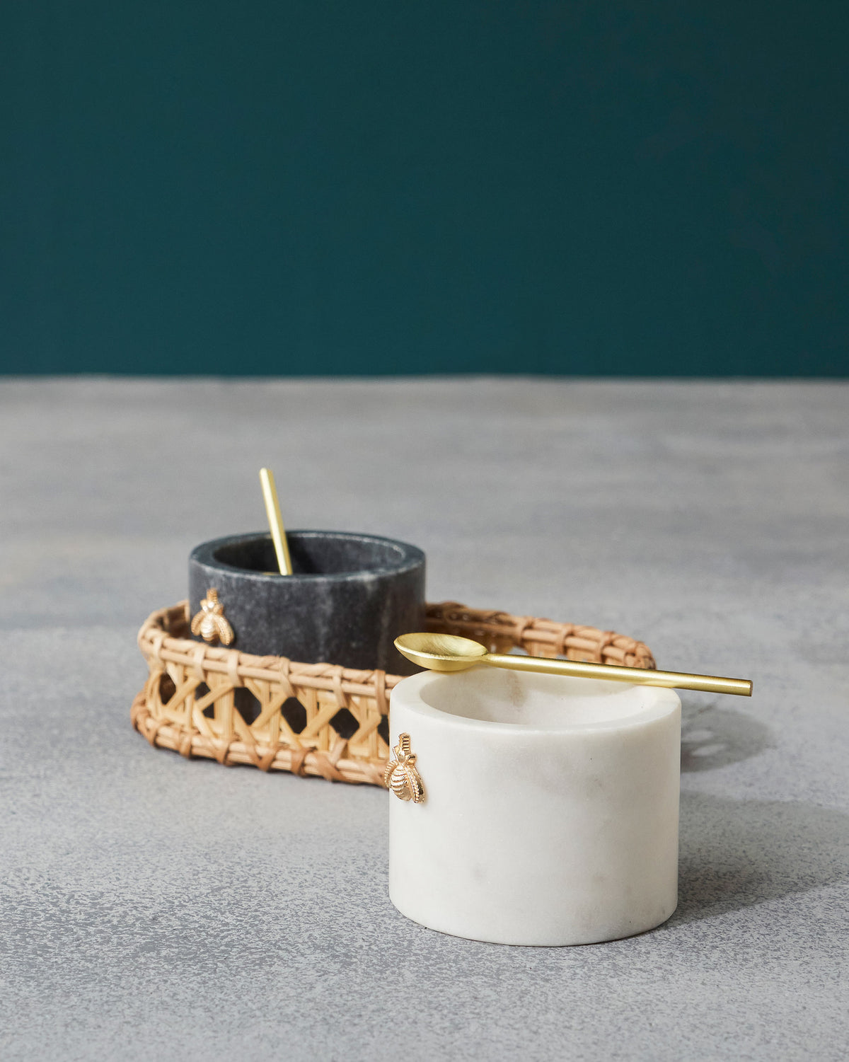 Garo white and charcoal marble pots with gold spoons and bee motifs.