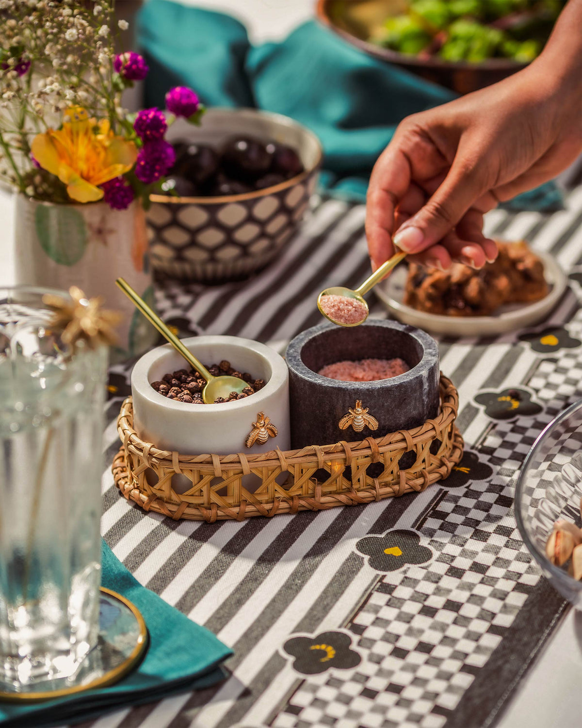 Garo salt and pepper pots in use on a dining table with gold spoons.