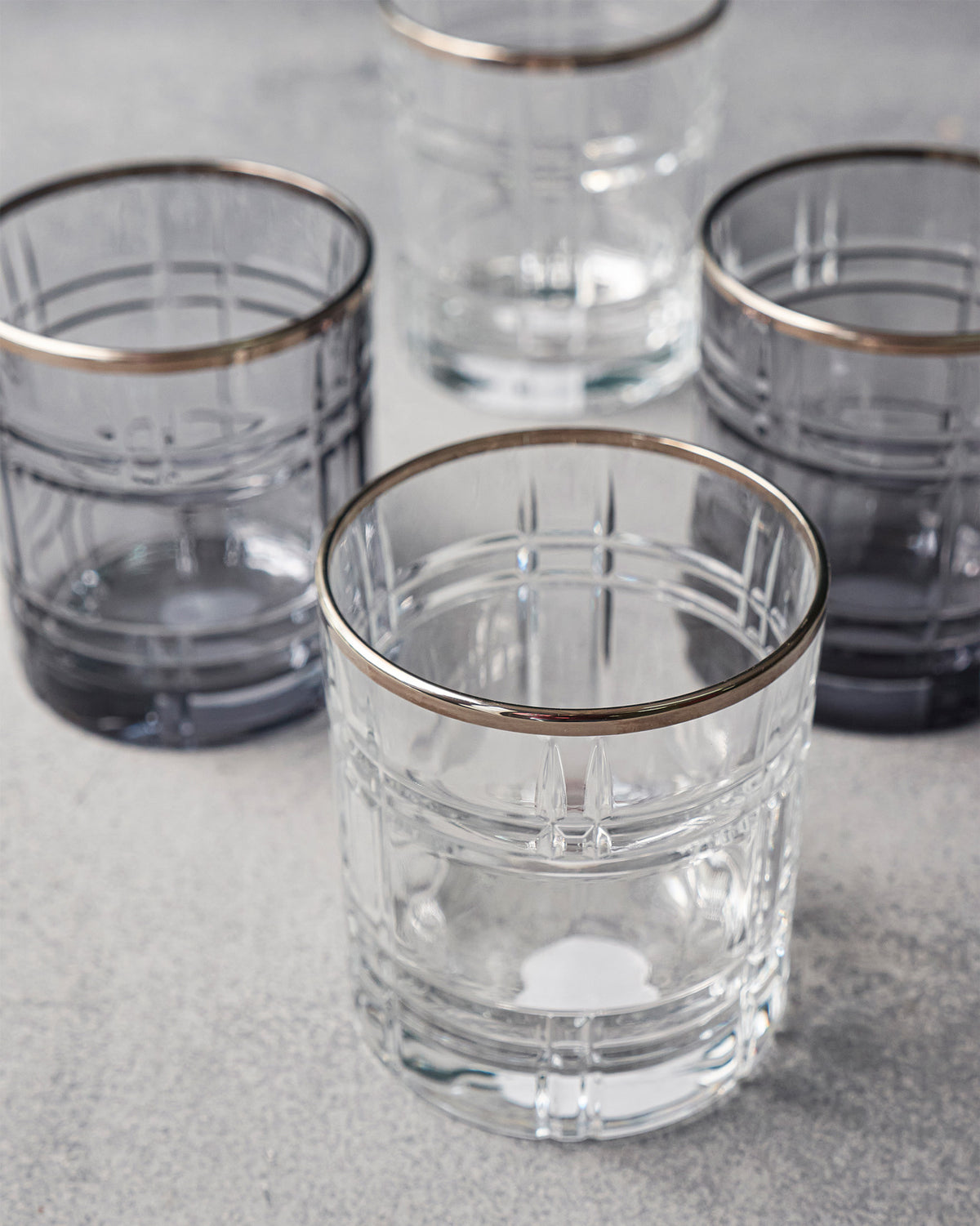 Four Celeste whiskey glasses in clear and smoke with gold rims.