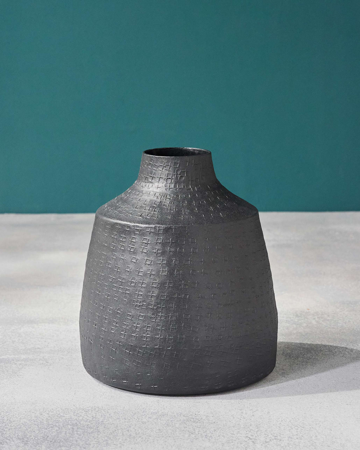 Dhaara Vase in black with a raised cross texture on its body and neck.
