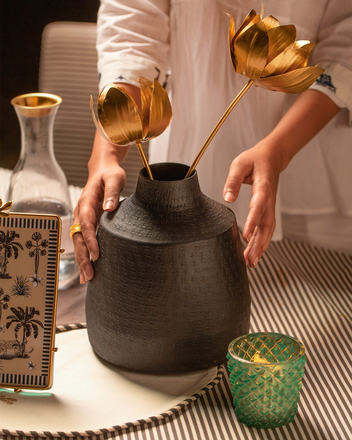 Person holding the Dhaara Vase with gold flowers.