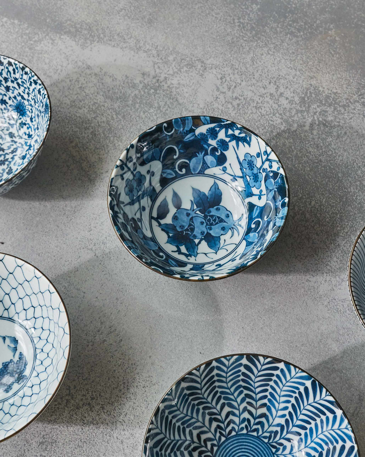 Blue and white Aiiro bowls clustered to show botanical and geometric patterns.
