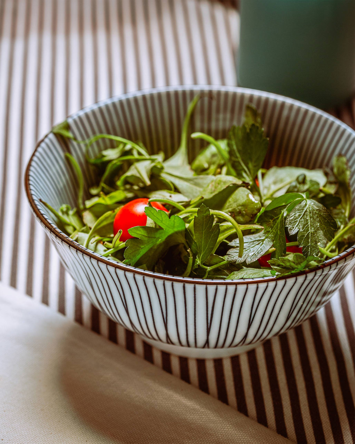 Pinstriped Aiiro snack bowl filled with a green salad.