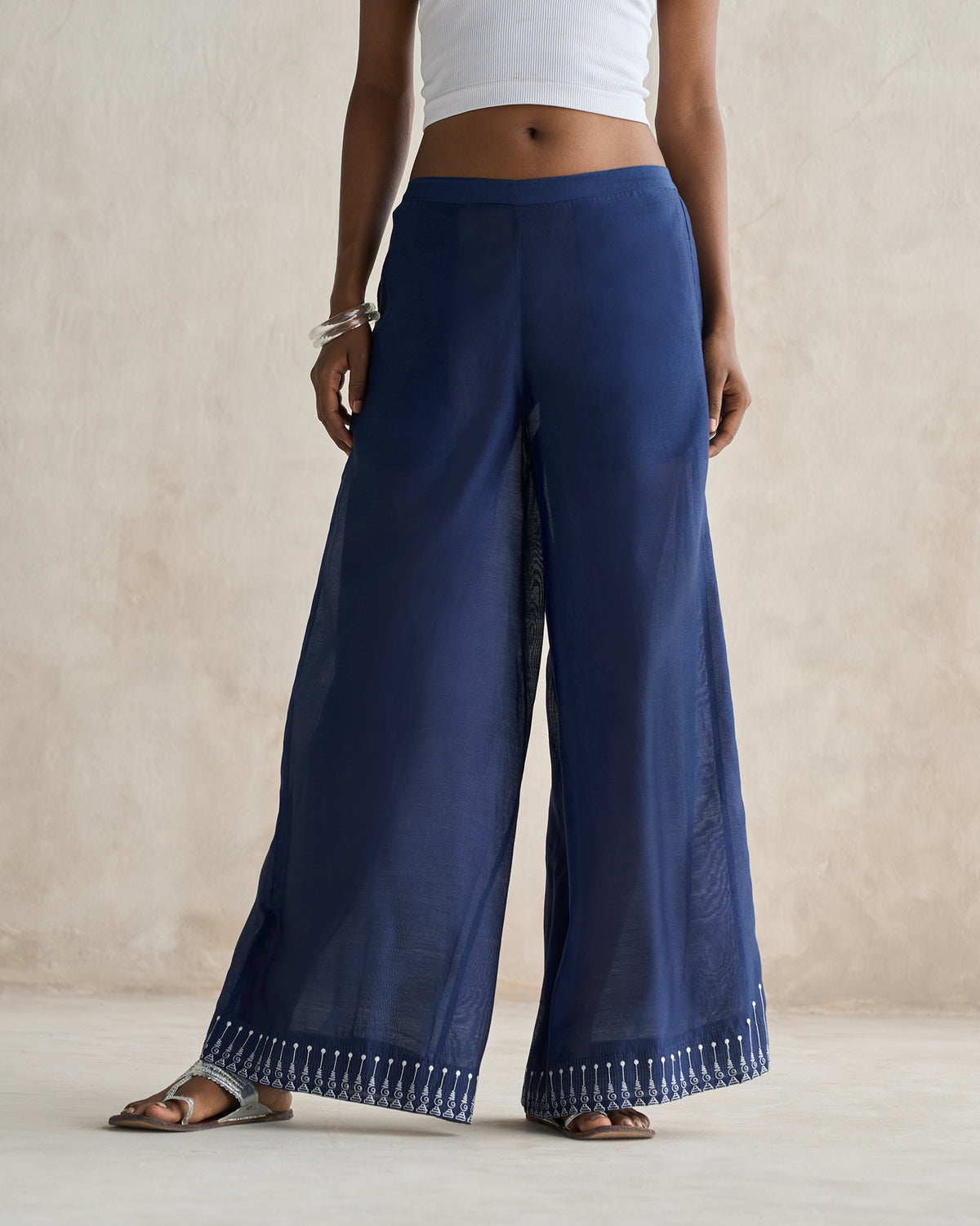 Person wearing navy sheer trousers with a white embroidered hem.