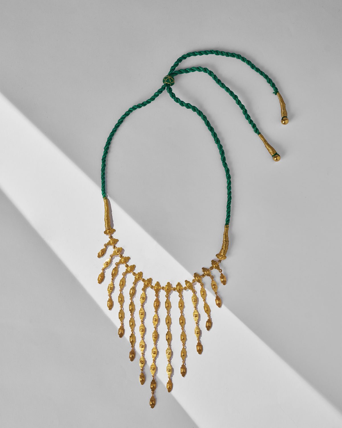 Gold zedi necklace with fringe drops on a green cord.
