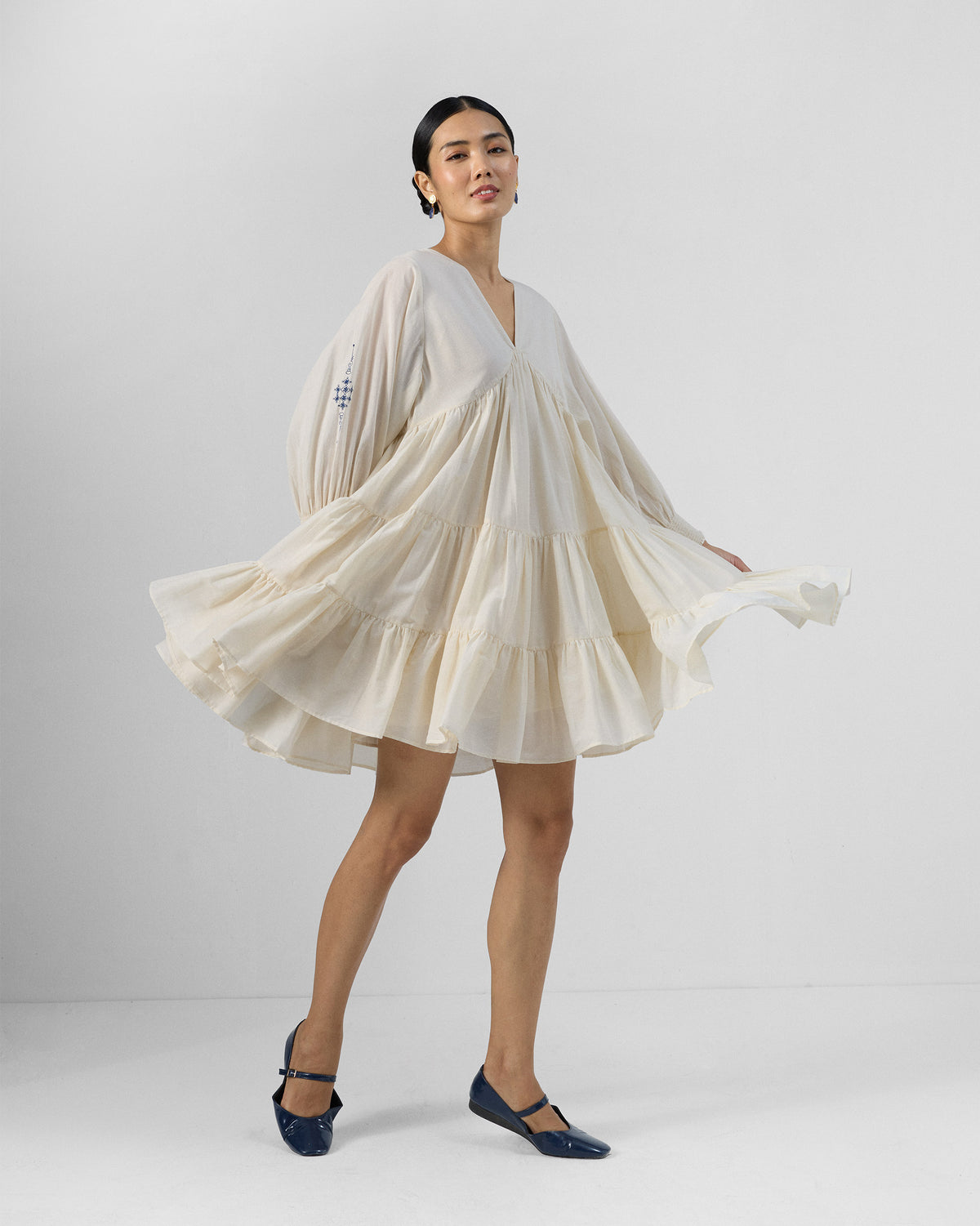 Person twirling in an ivory Temple tier dress with gathered sleeves.