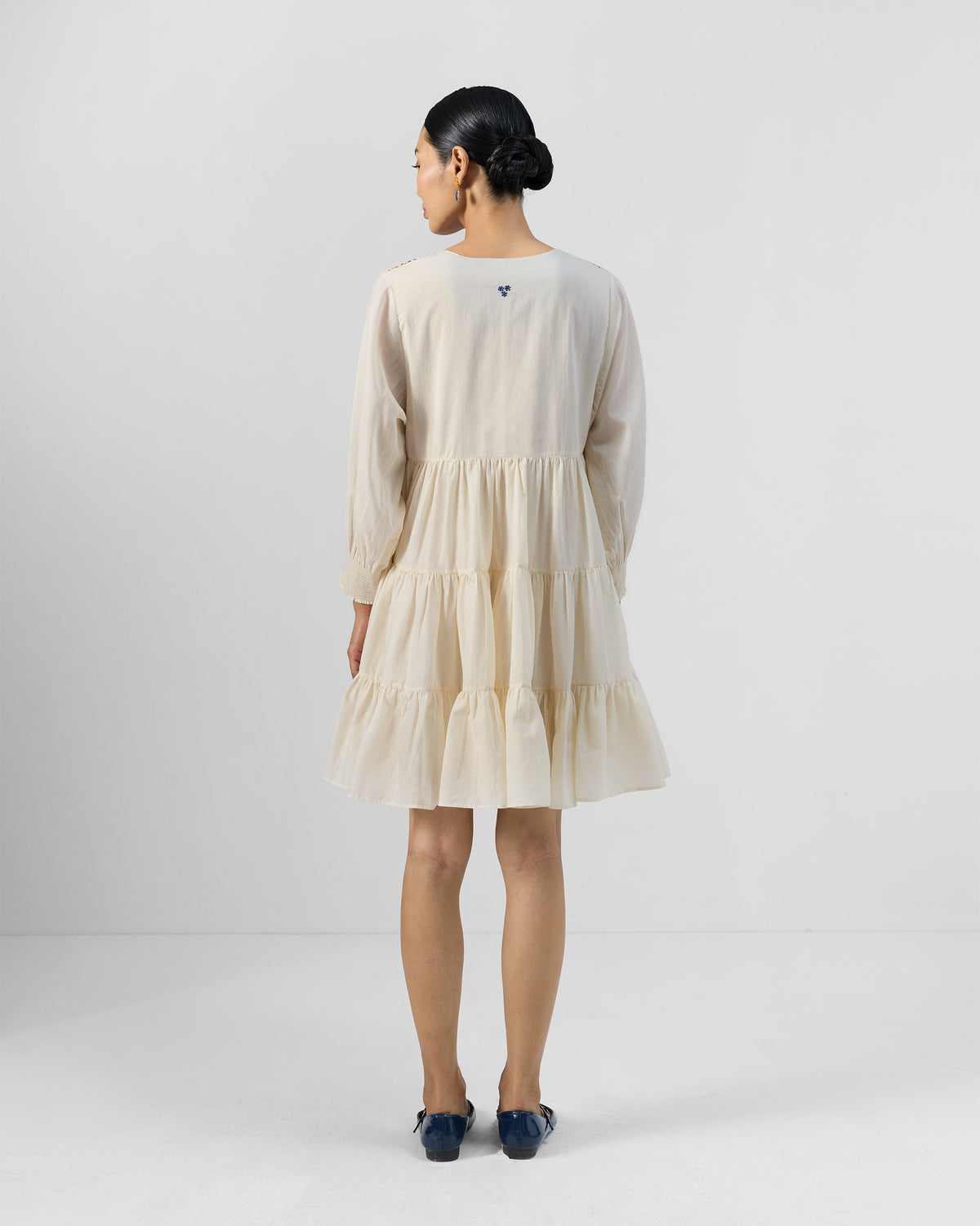 Back of an ivory Temple tier dress with a small blue neck motif.
