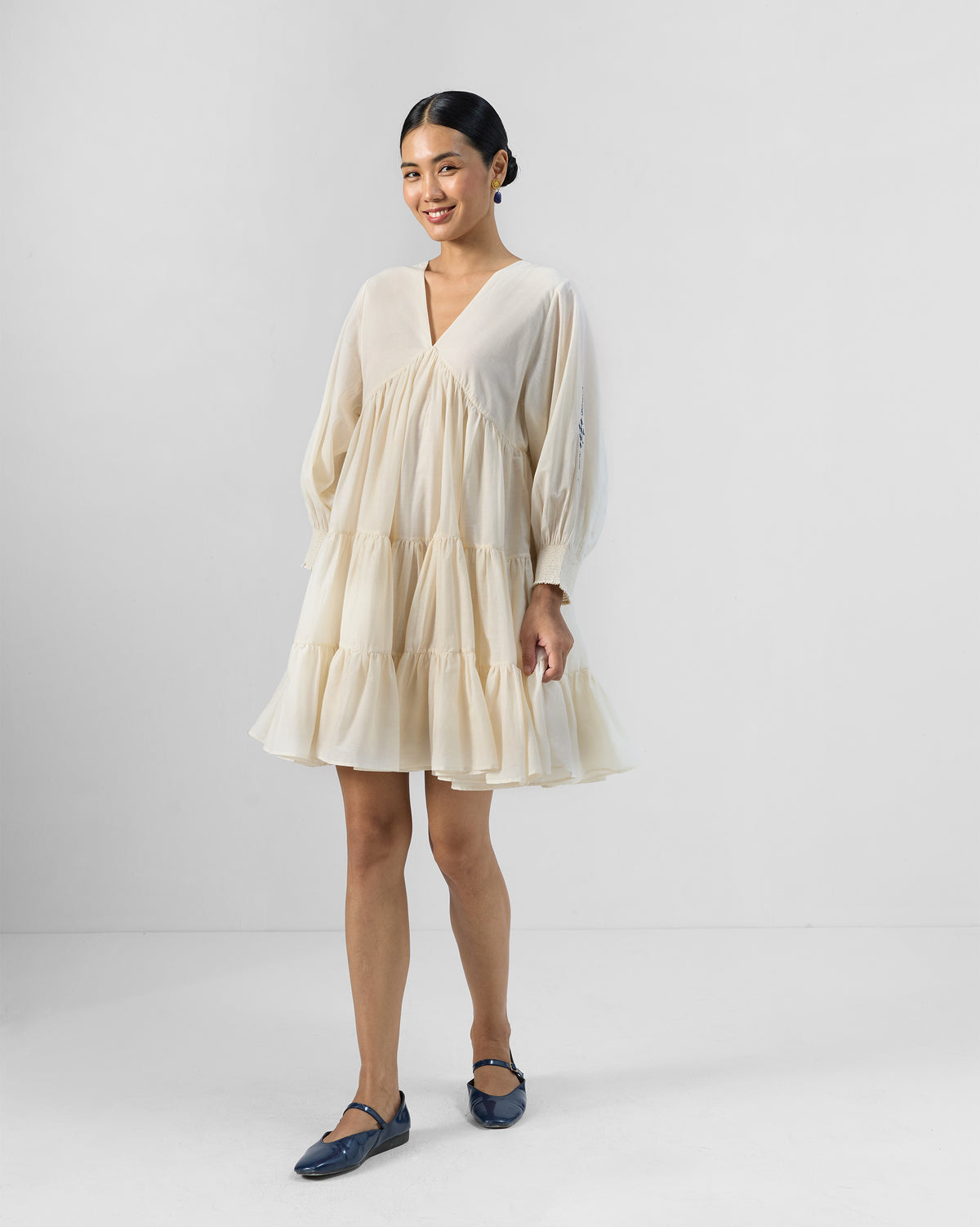 Person wearing an ivory Temple tier dress with long sleeves.