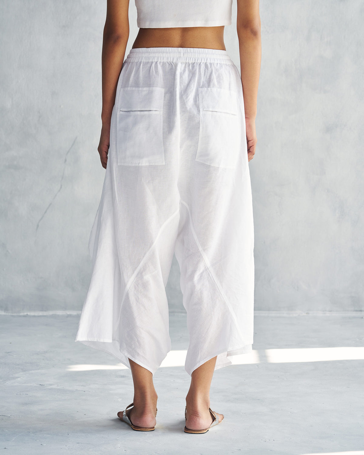 Back of white Yoka Trousers with patch pockets worn by a person.
