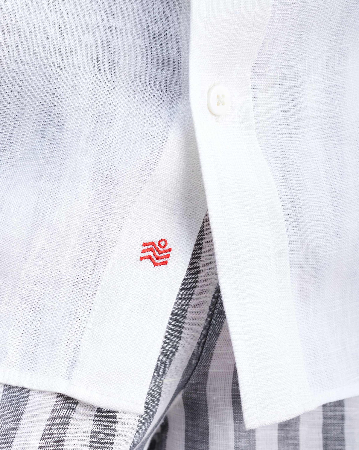 Close-up of red embroidery near the hem of a white half-sleeve shirt.