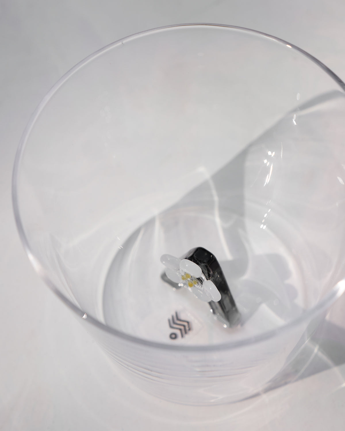 Looking down into a clear glass with a white flower motif at the base.