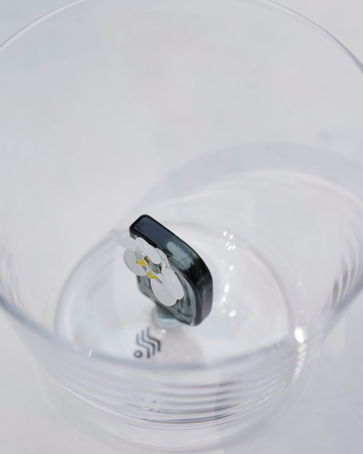 Looking down into a clear glass with a white flower motif at the base.
