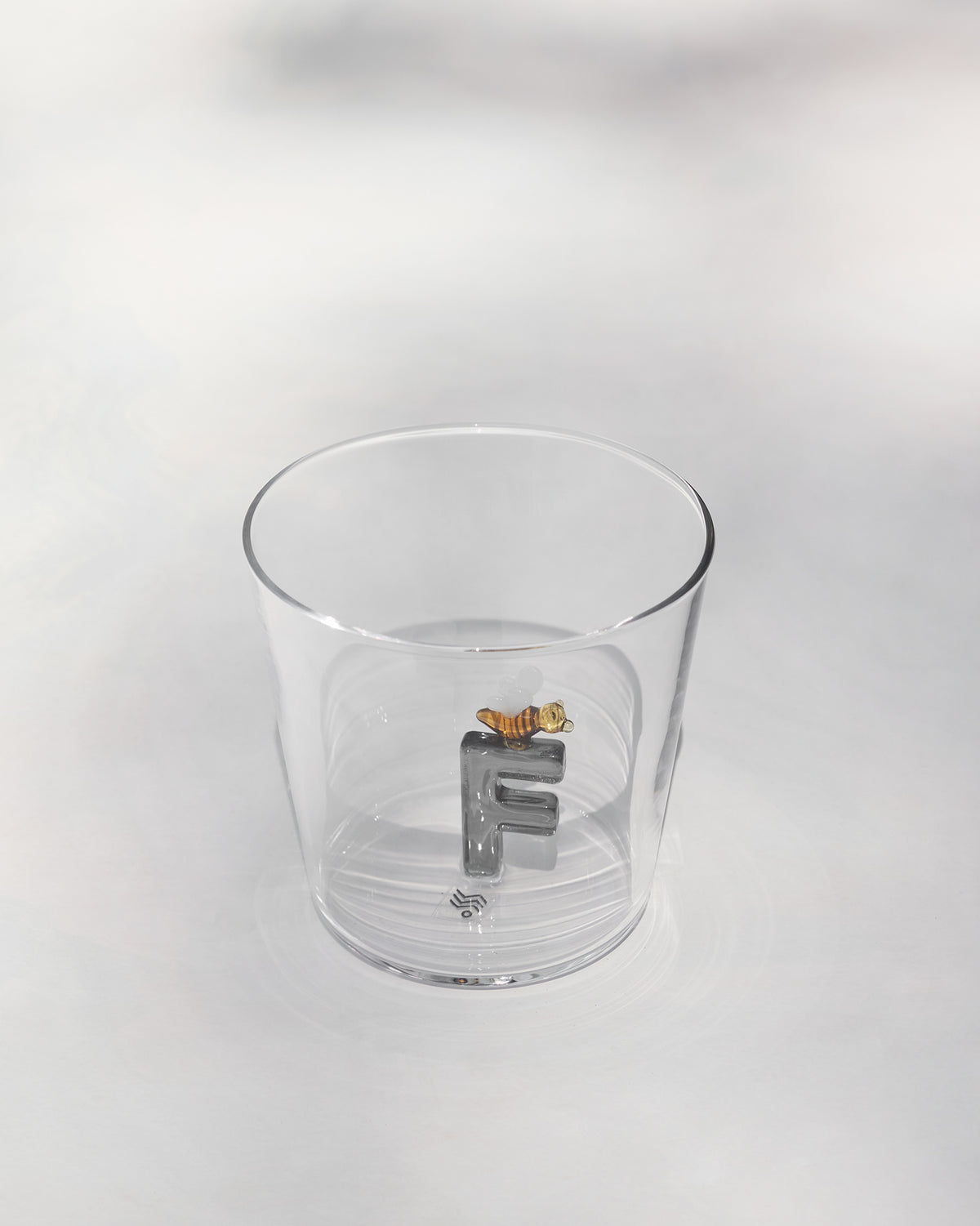 Clear tumbler with a 3D letter F topped by a tiny bee at the base.