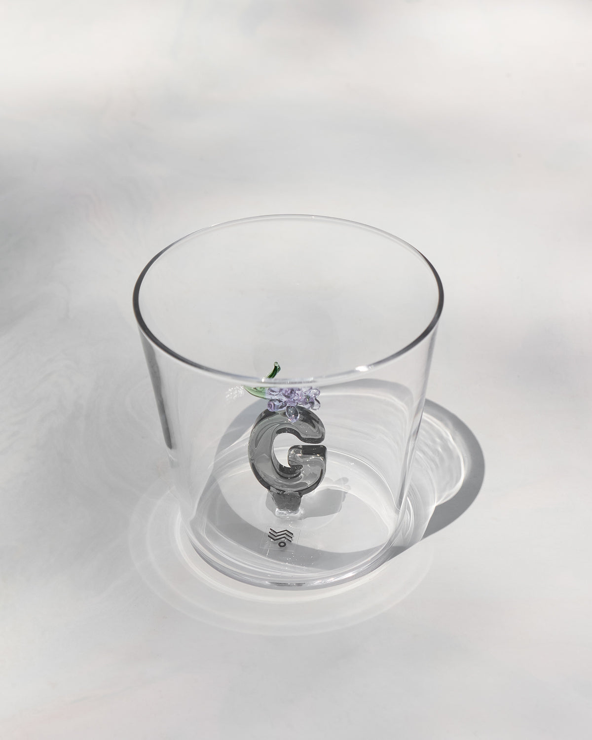 Clear tumbler with a 3D letter G topped by purple flowers at the base.