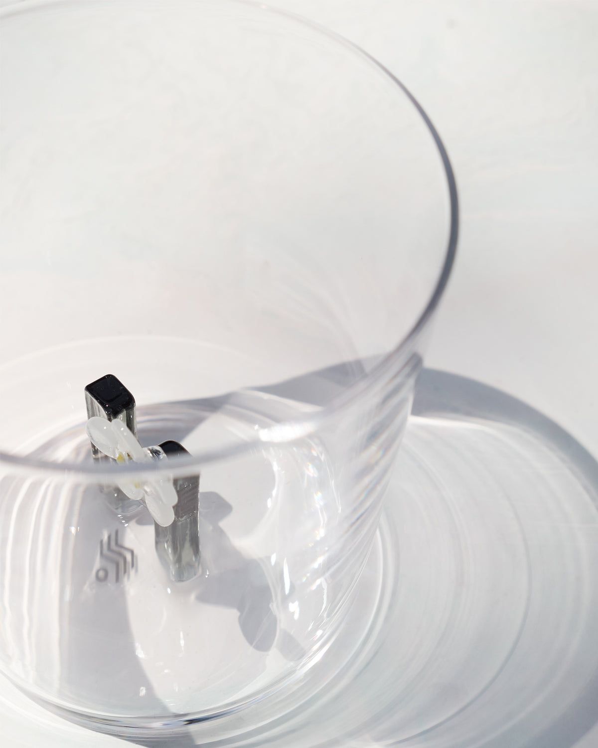 Looking down into a clear glass with a white flower motif at the base.