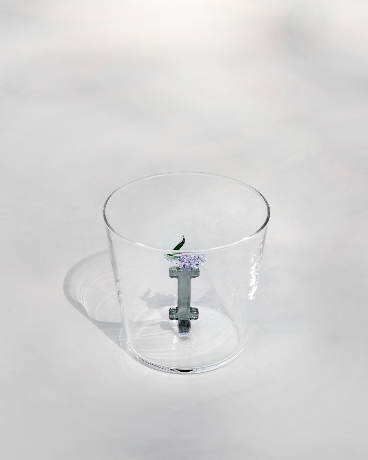 Clear tumbler with a 3D letter I topped by purple flowers and a green leaf.