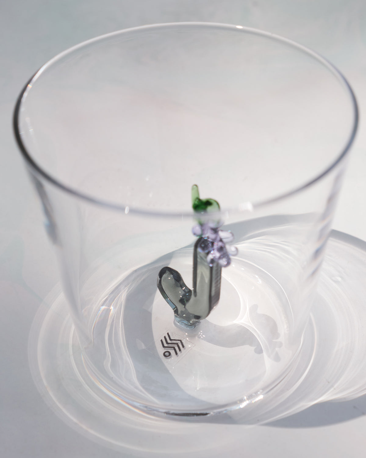 Looking down into a clear glass with a letter J topped by purple flowers.