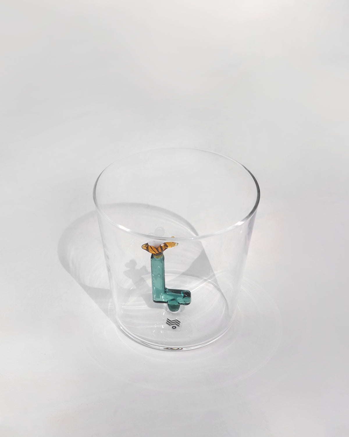 Close-up of a teal letter L with an amber butterfly inside a clear Alphabet glass.