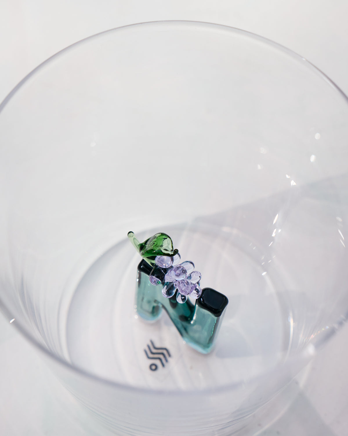 Overhead view of an Alphabet glass with a teal floral letter N.