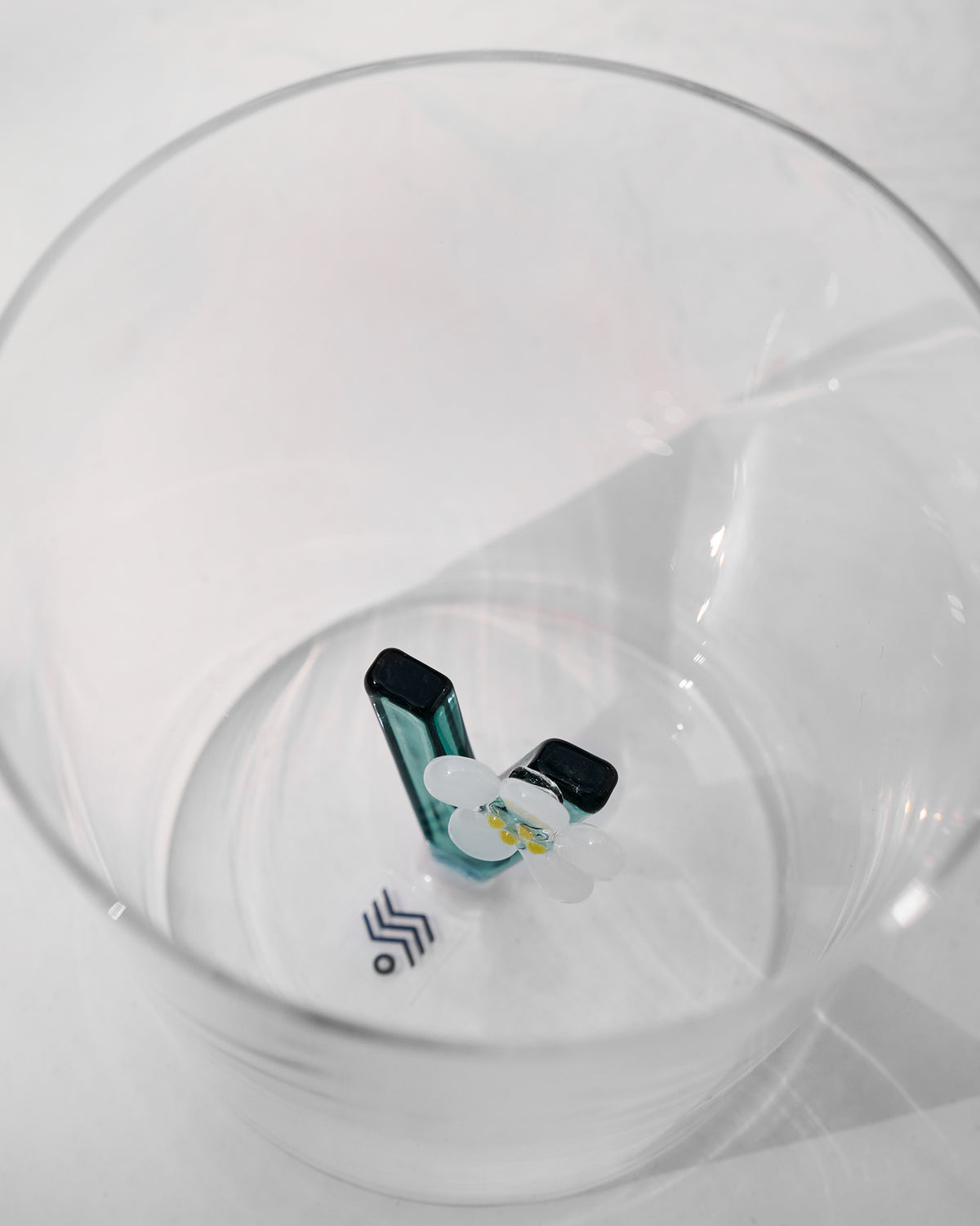 Overhead view of an Alphabet glass with a teal floral letter V.