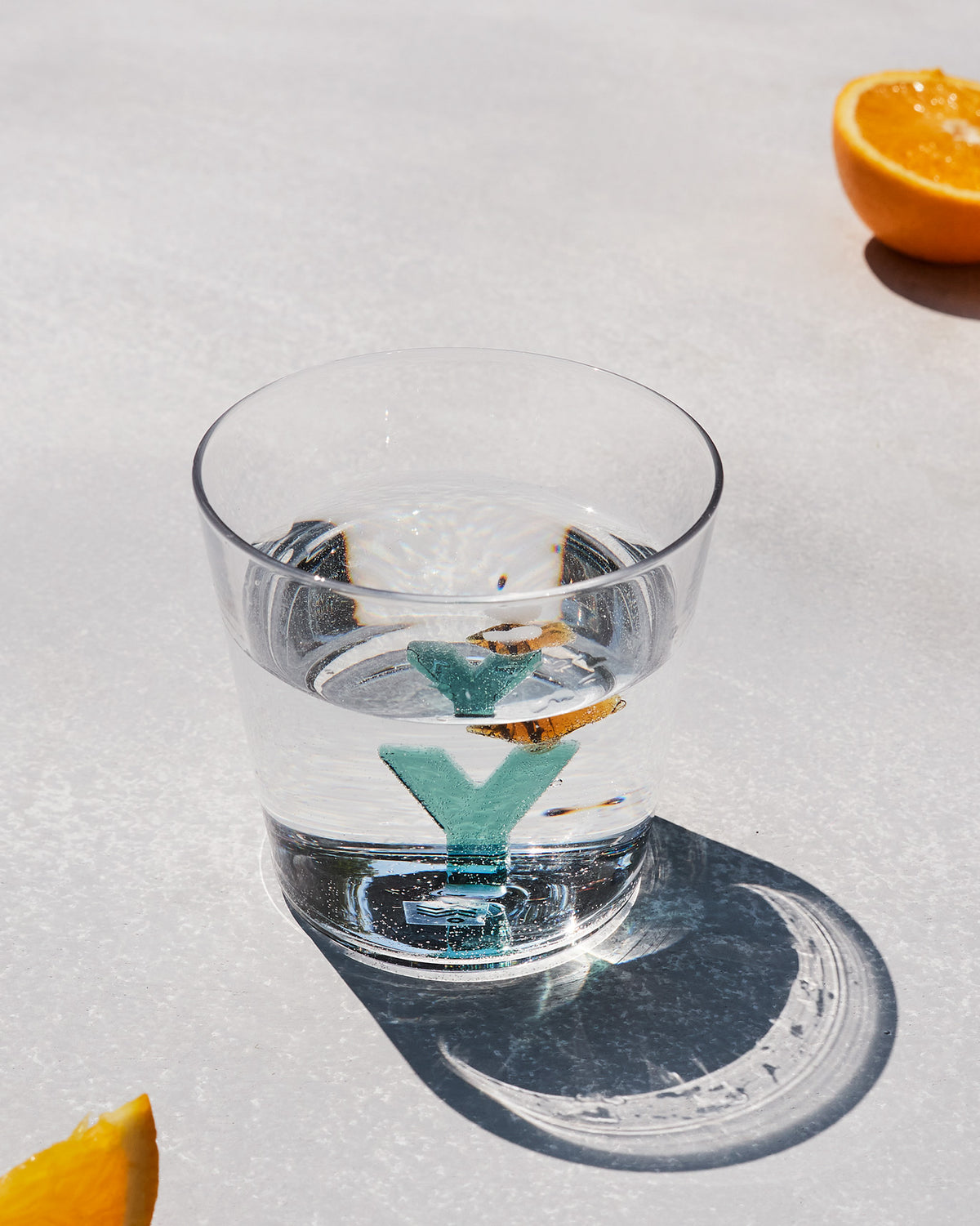 Clear Alphabet glass with a teal letter Y, half filled with water.