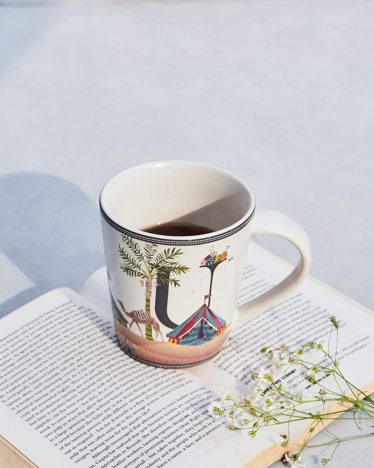 Cream Umbrella alphabet mug with letter U, camel and tent, filled with coffee.