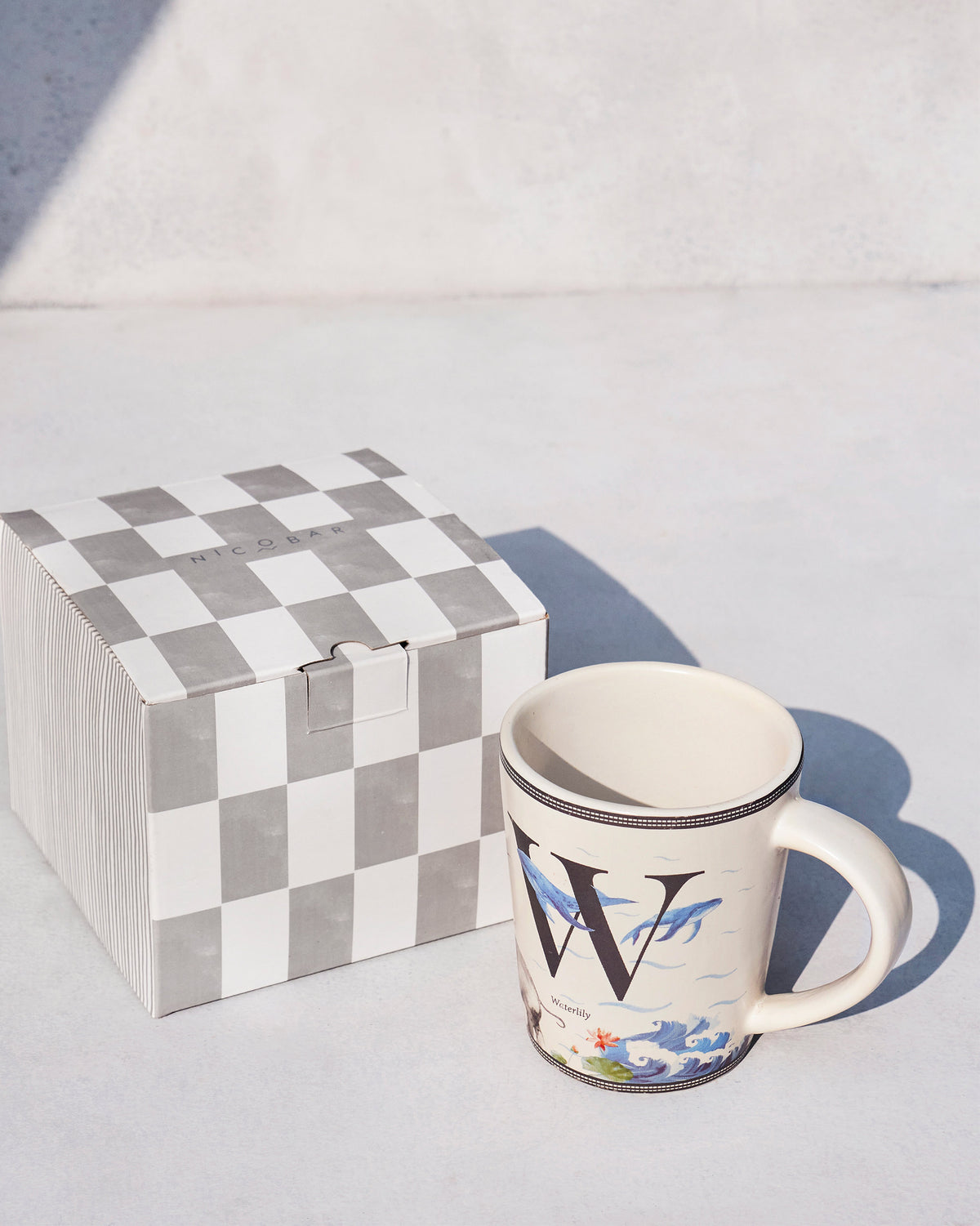 Waterlily mug standing beside its grey check Nicobar gift box.