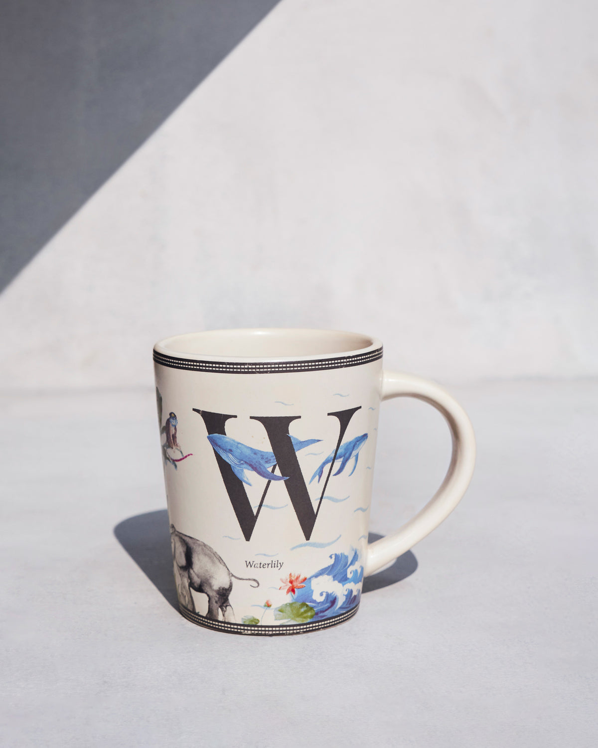 Cream Waterlily mug with a large W, whales and a waterlily.