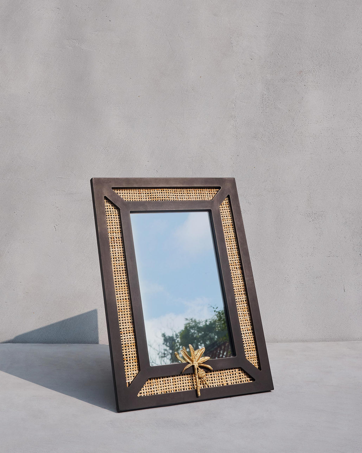 Pondicherry Mirror standing at an angle, showing its black frame and cane panels.