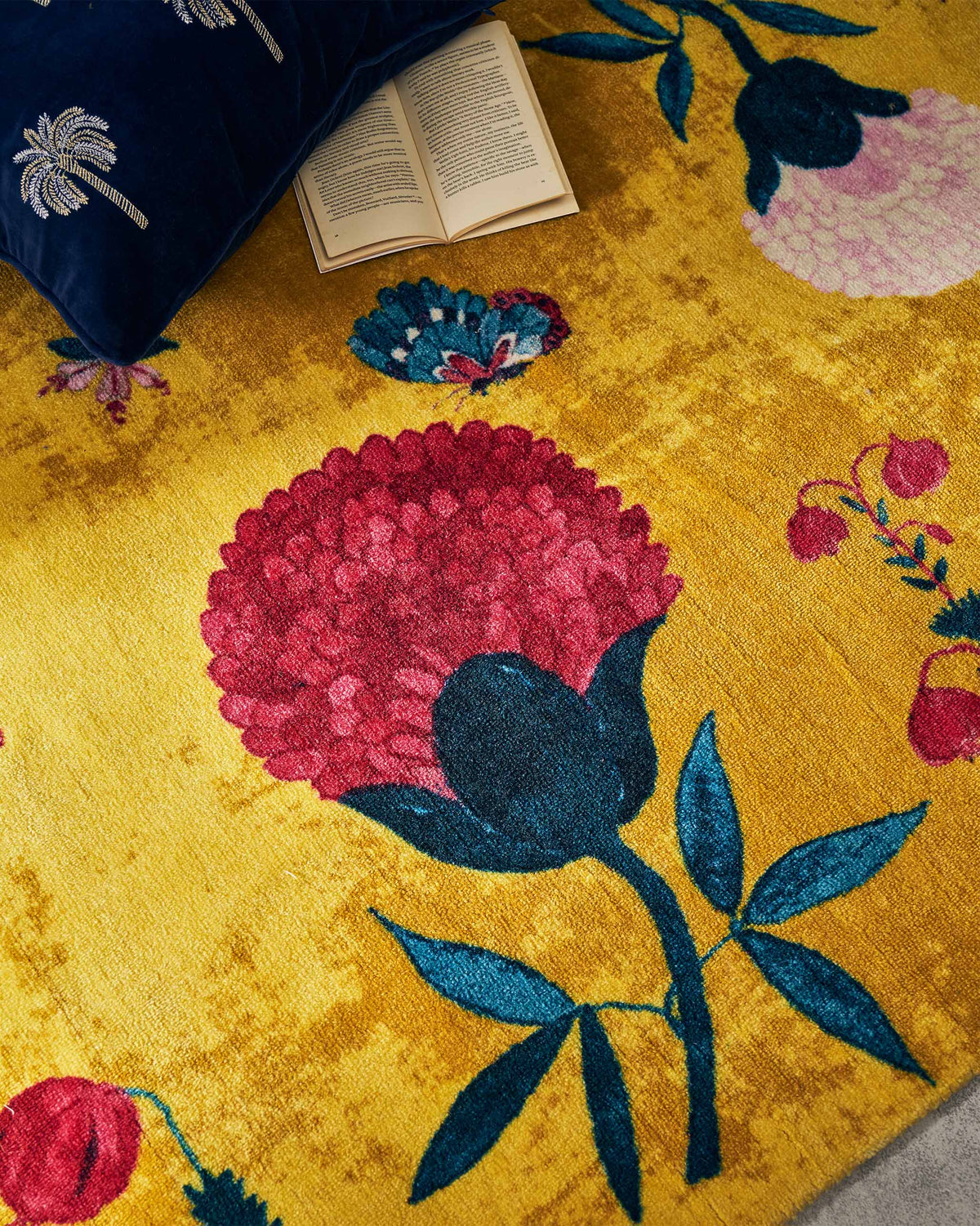 Close-up of Woodland Rug in yellow showing its red bloom and teal leaves.