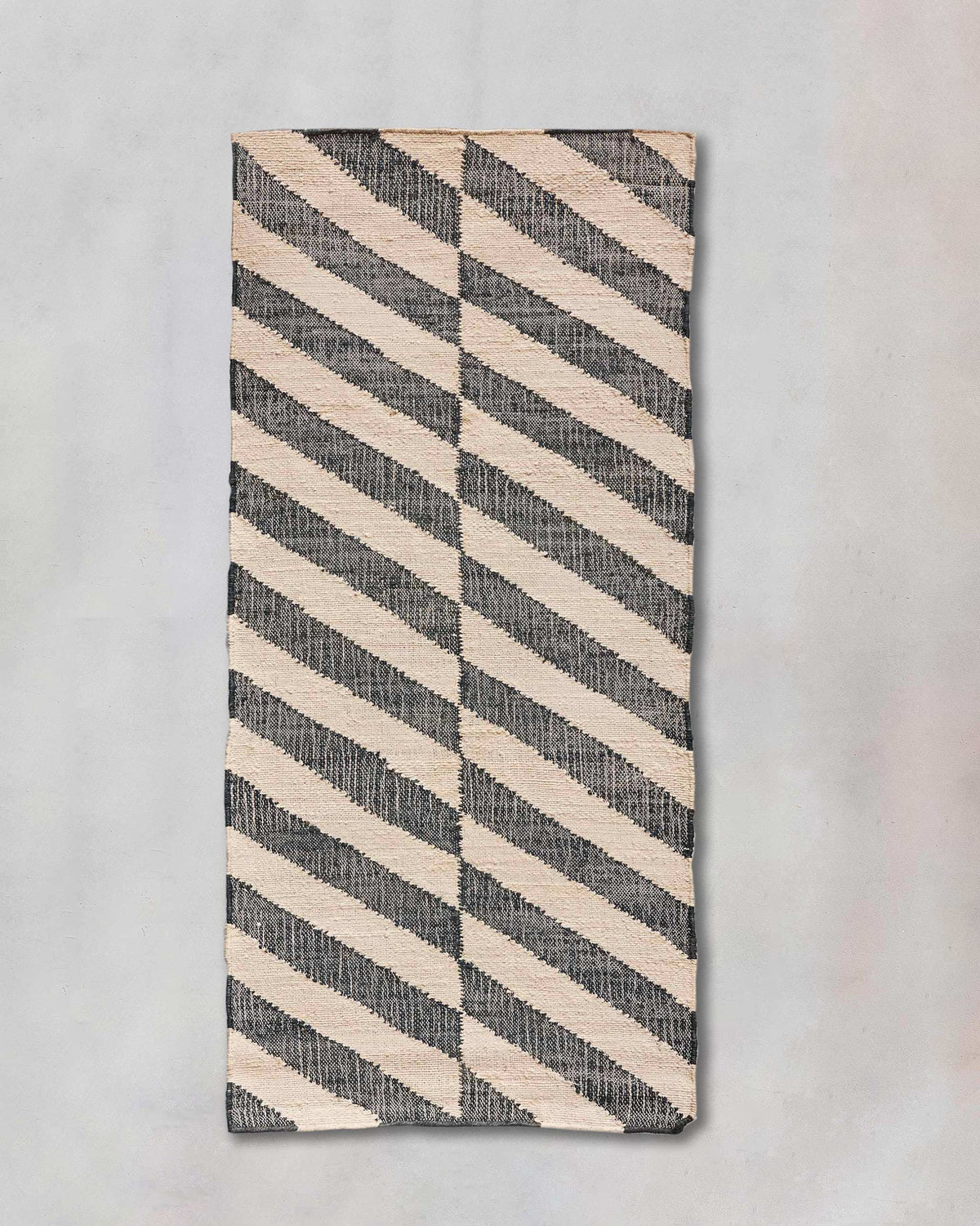 Nico Rug with charcoal and cream diagonal stripes, shown flat.