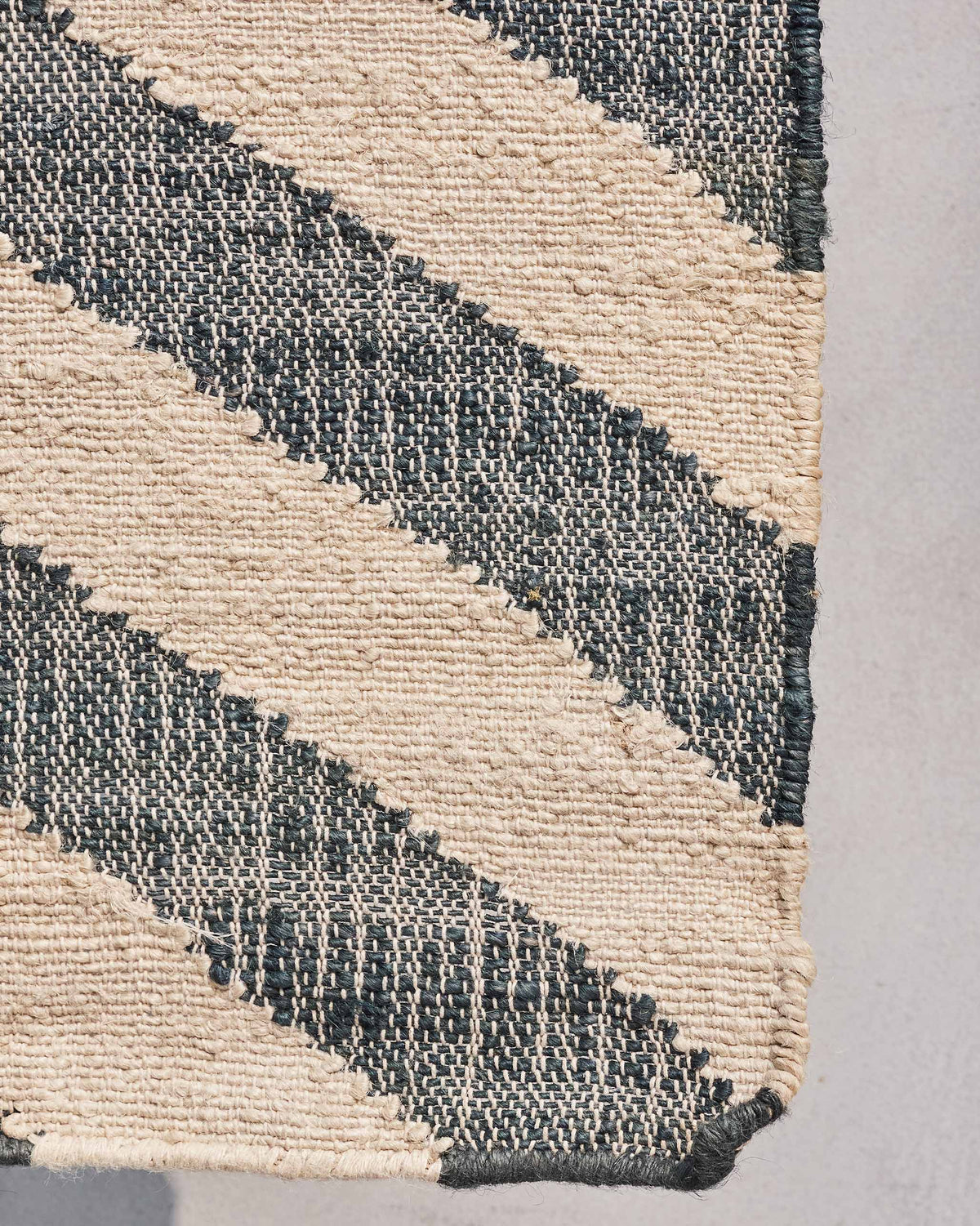 Close-up of Nico Rug corner showing its cream and charcoal woven texture.