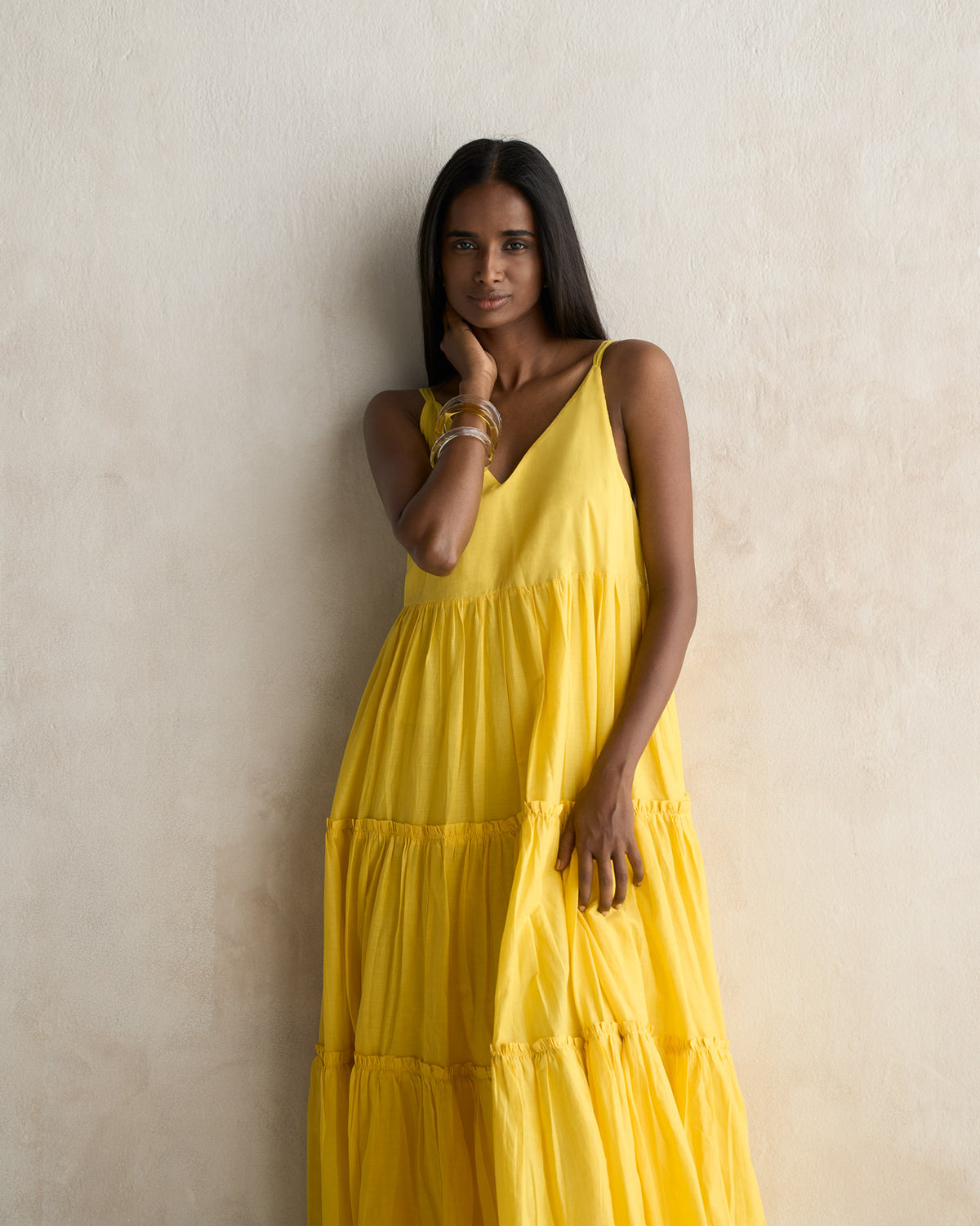 Person wearing a yellow tiered dress with gathered ruffle tiers.