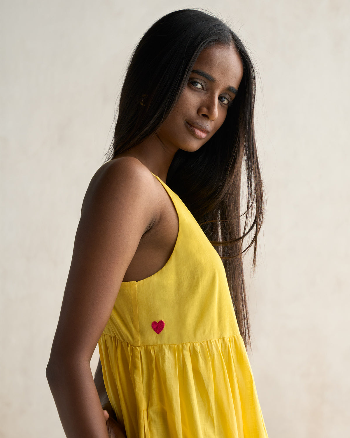 Person wearing a yellow tiered dress with a red heart on the bodice.