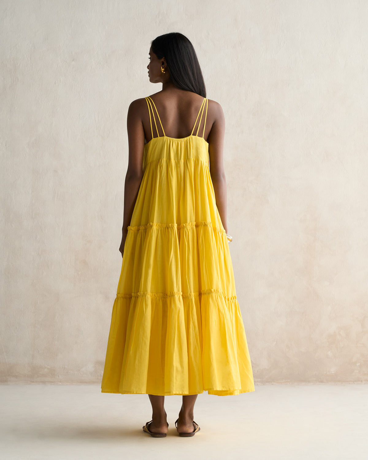 Back of a yellow tiered maxi dress with multiple spaghetti straps.