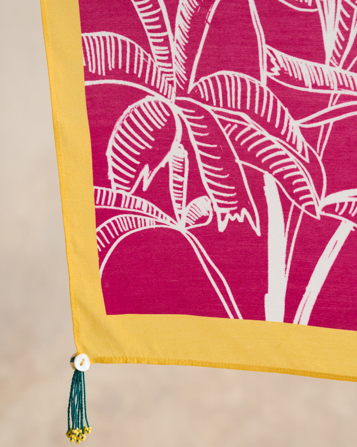 Close-up of a Padma scarf corner showing white palm leaf prints and a yellow border.