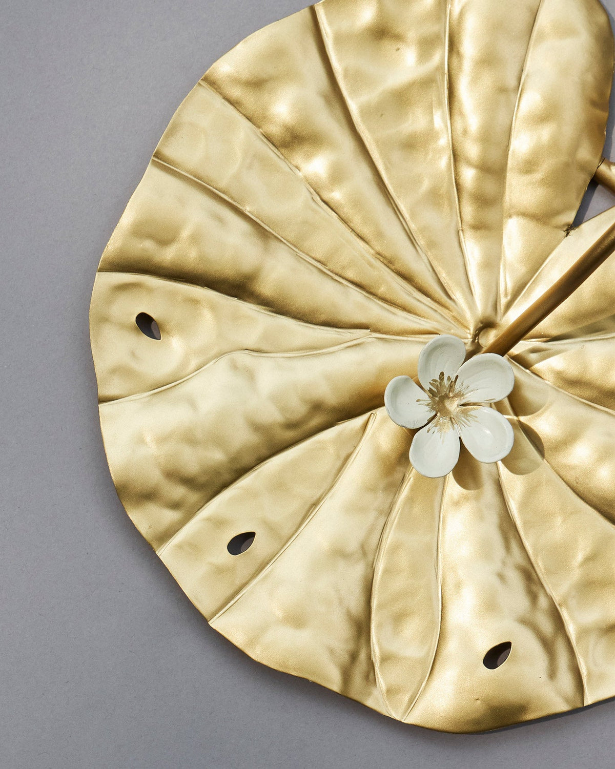 Close-up of the hammered gold Padma leaf with a small white flower.