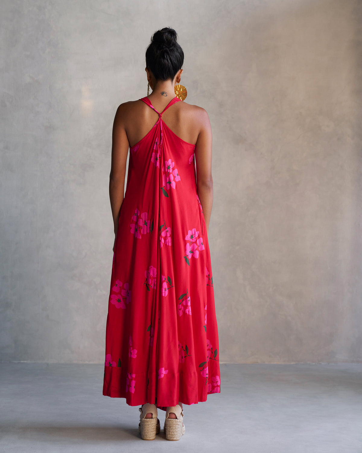 Back of the red Akira Twist Back Dress with a twisted halter strap, worn by a person.