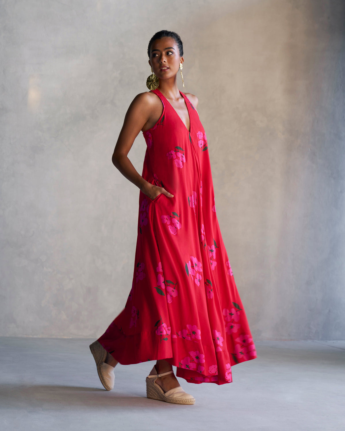 Person wearing a long red Akira Twist Back Dress with pink flowers.