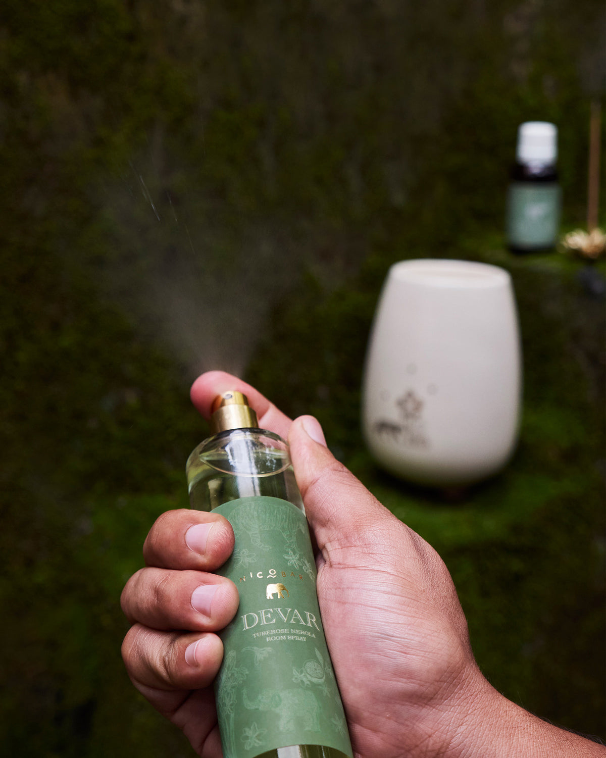 Hand spraying Devar Tuberose Neroli room spray from a gold nozzle.